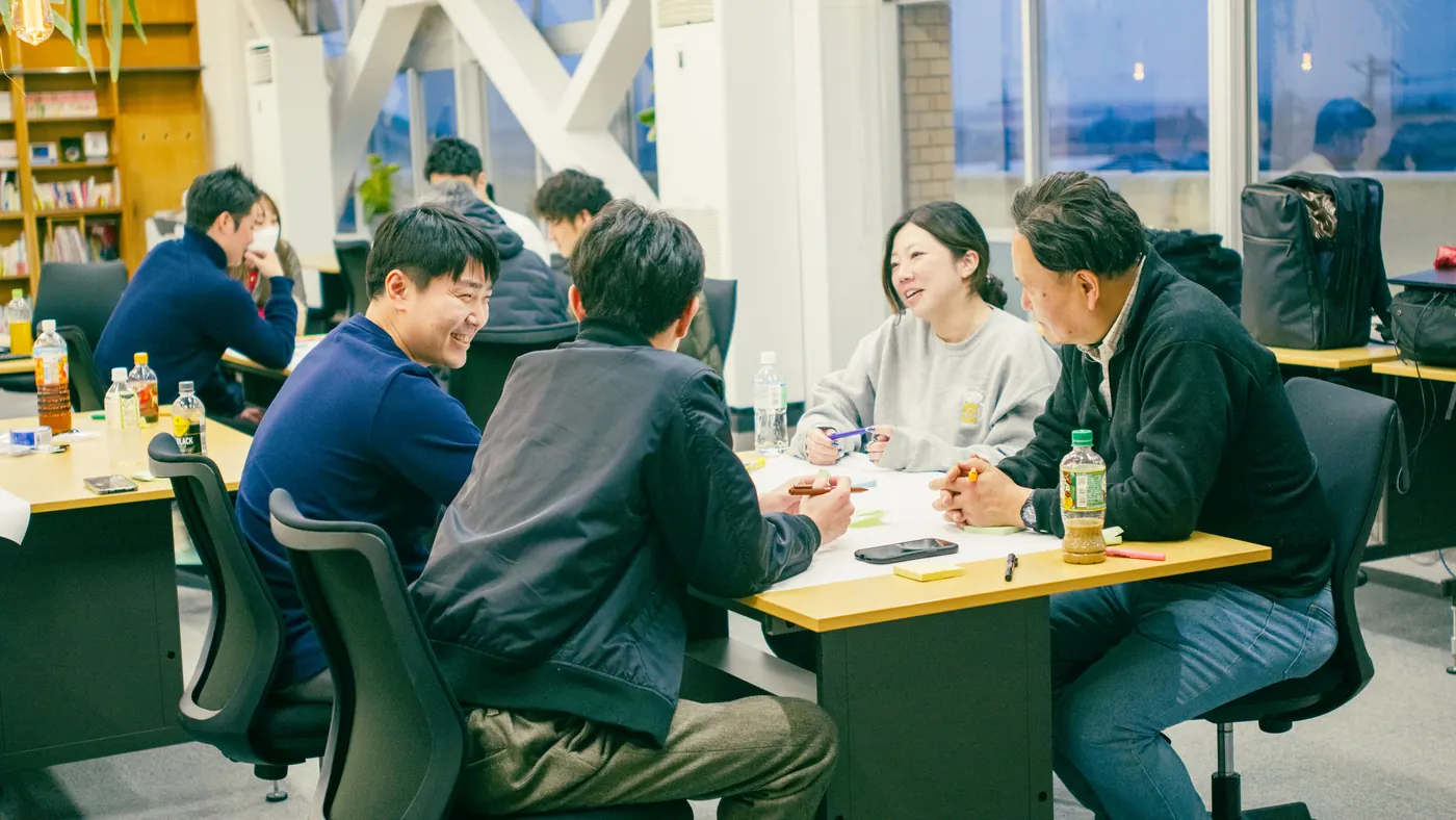 旧石出小学校の教室で、テーブルを囲んで話し合う人たち